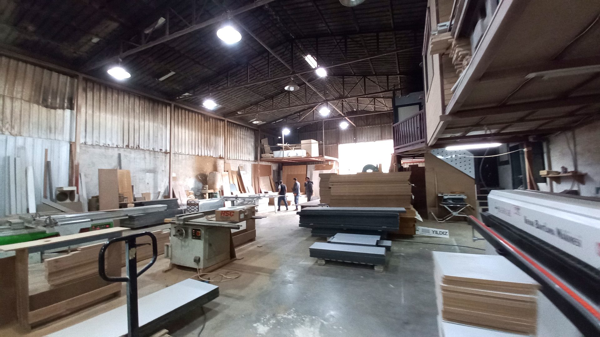 Sliding panel saw and stacks of MDF and melamine board in the ReFix furniture workshop in Alanya
